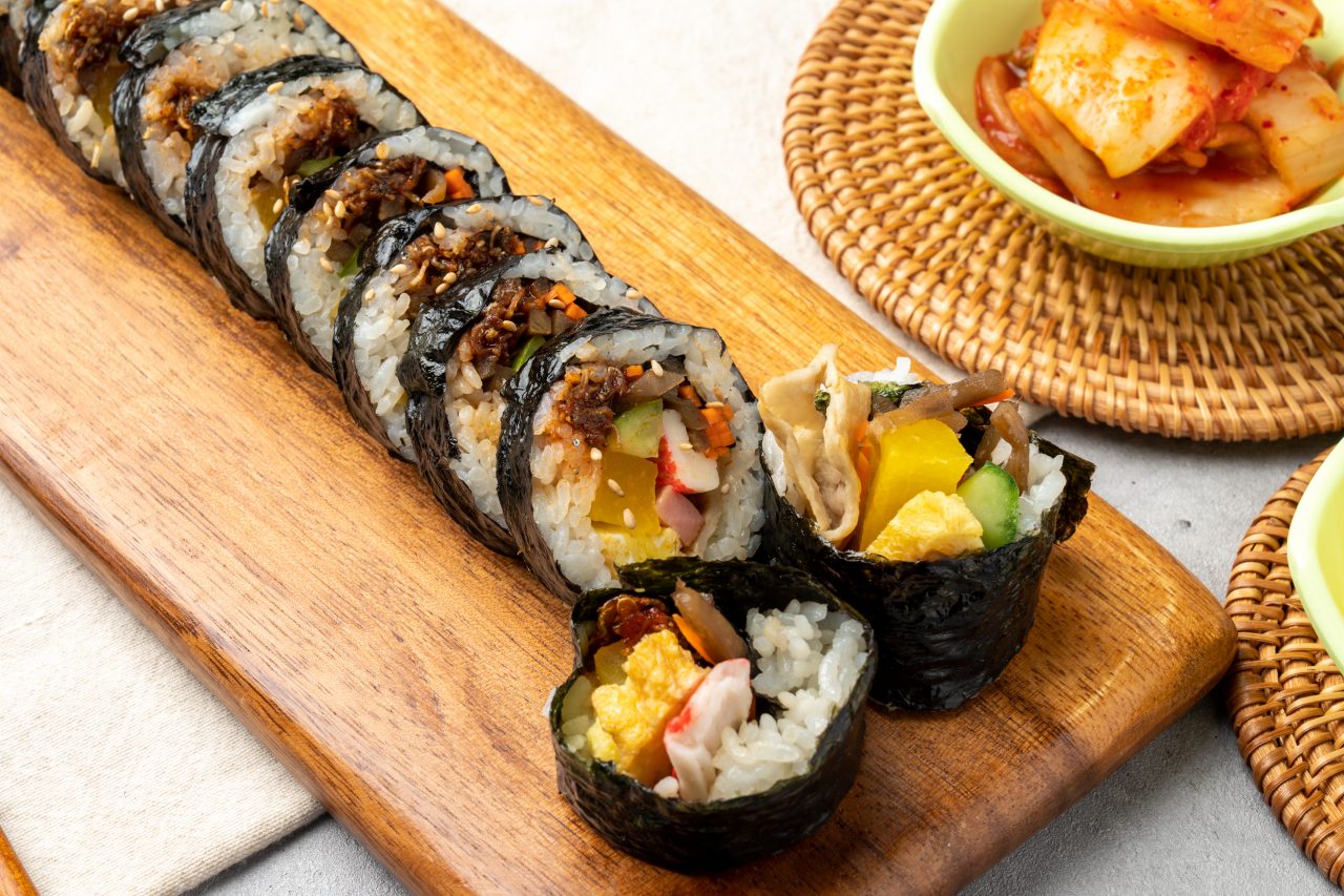 Korean food Kimbap served on a wooden cutting board.