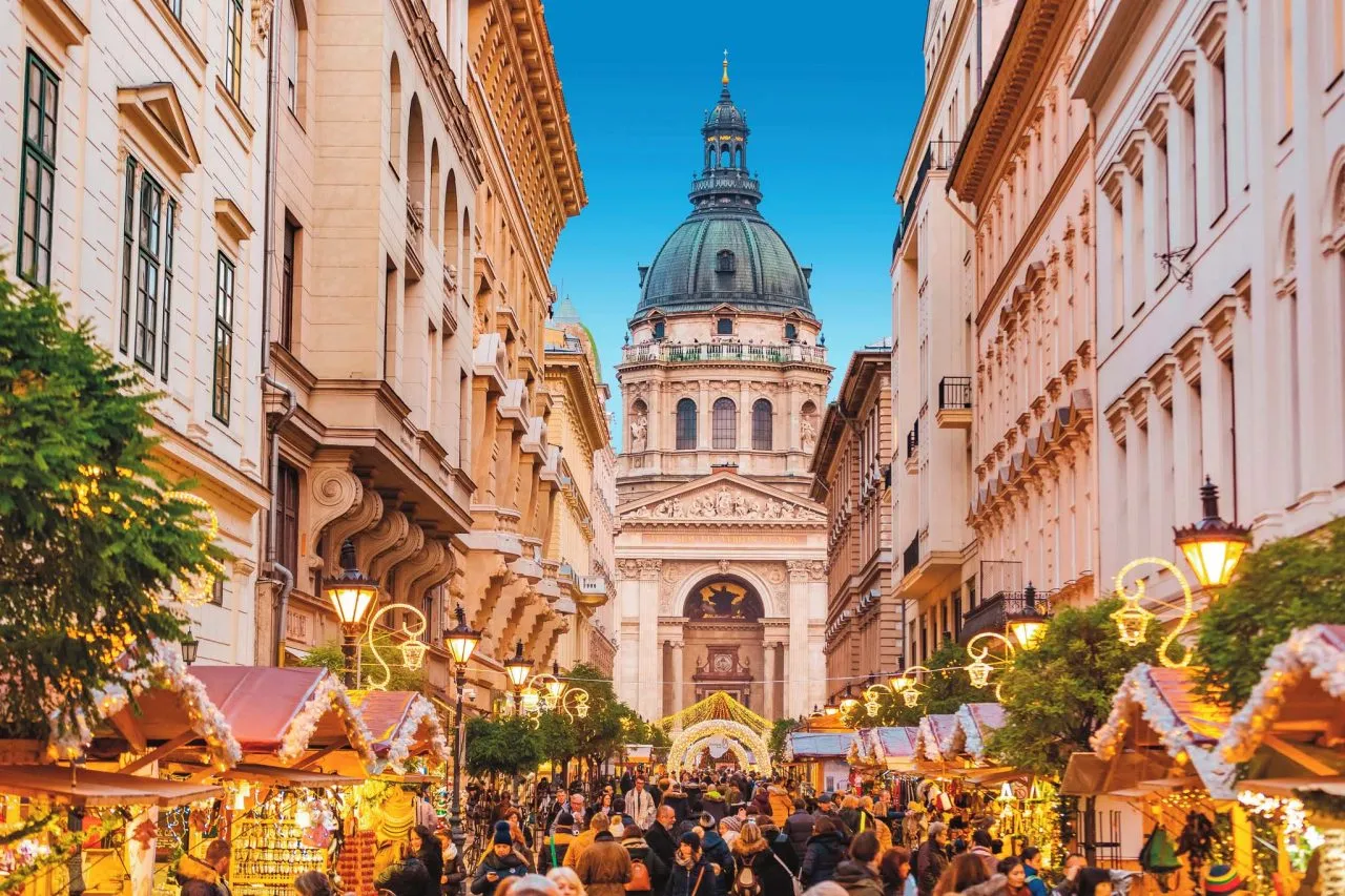 Festive street market leading to a grand domed cathedral, decorated with lights