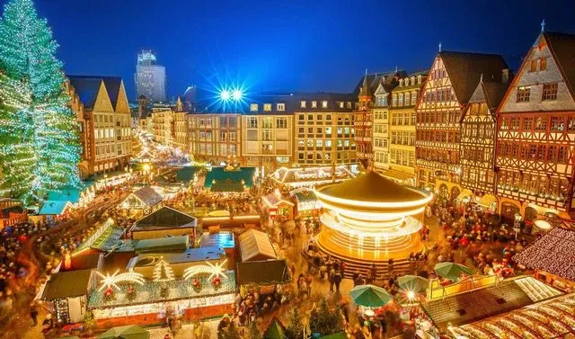 Large Christmas market square at night with a decorated tree and crowded stalls