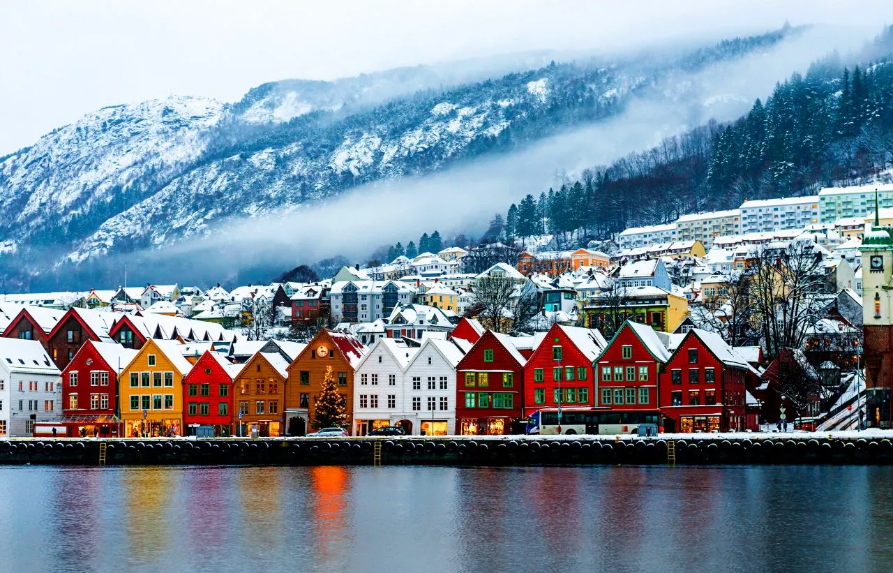Colorful waterfront houses with snowy mountains and mist in the background