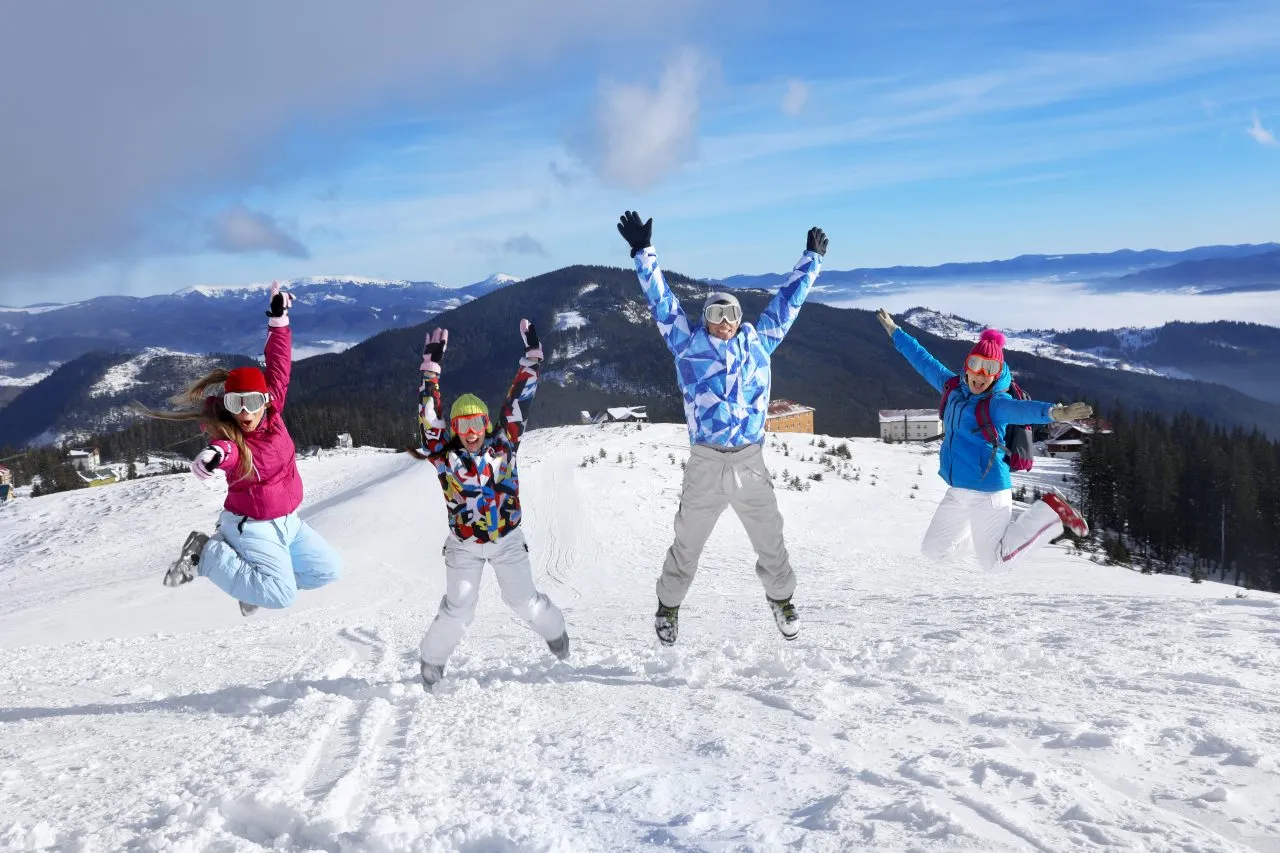 Group of friends jumping in the snow on a mountain with scenic views