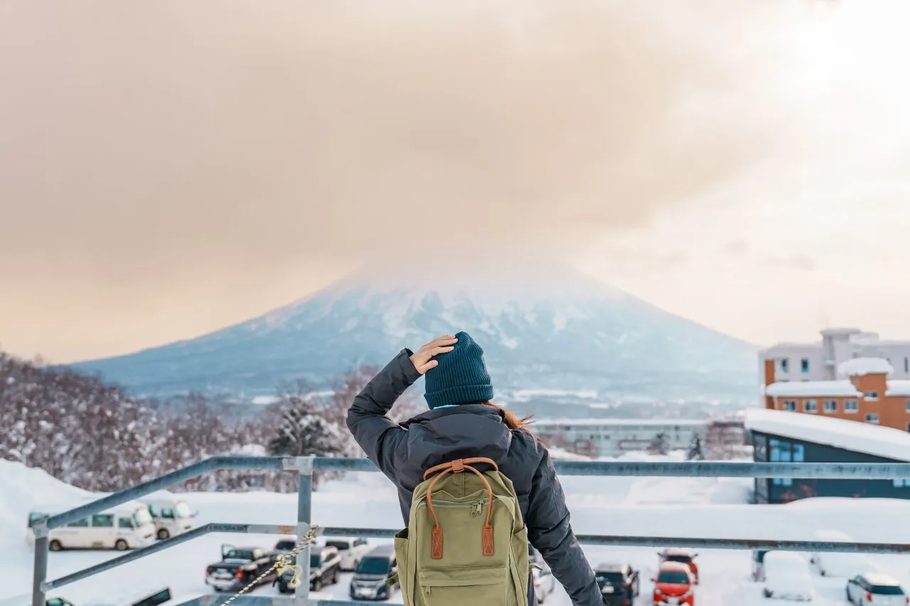 Person with a backpack looking at a snow-covered mountain from a viewpoint