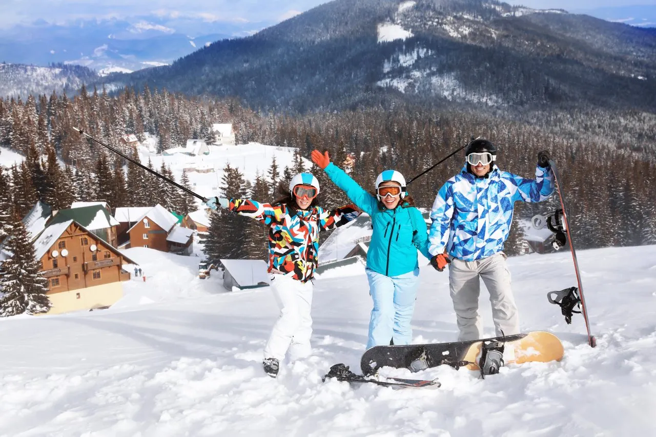 Skiers and snowboarders posing on snowy slopes in the Carpathian Mountains, surrounded by alpine cabins and pine forests