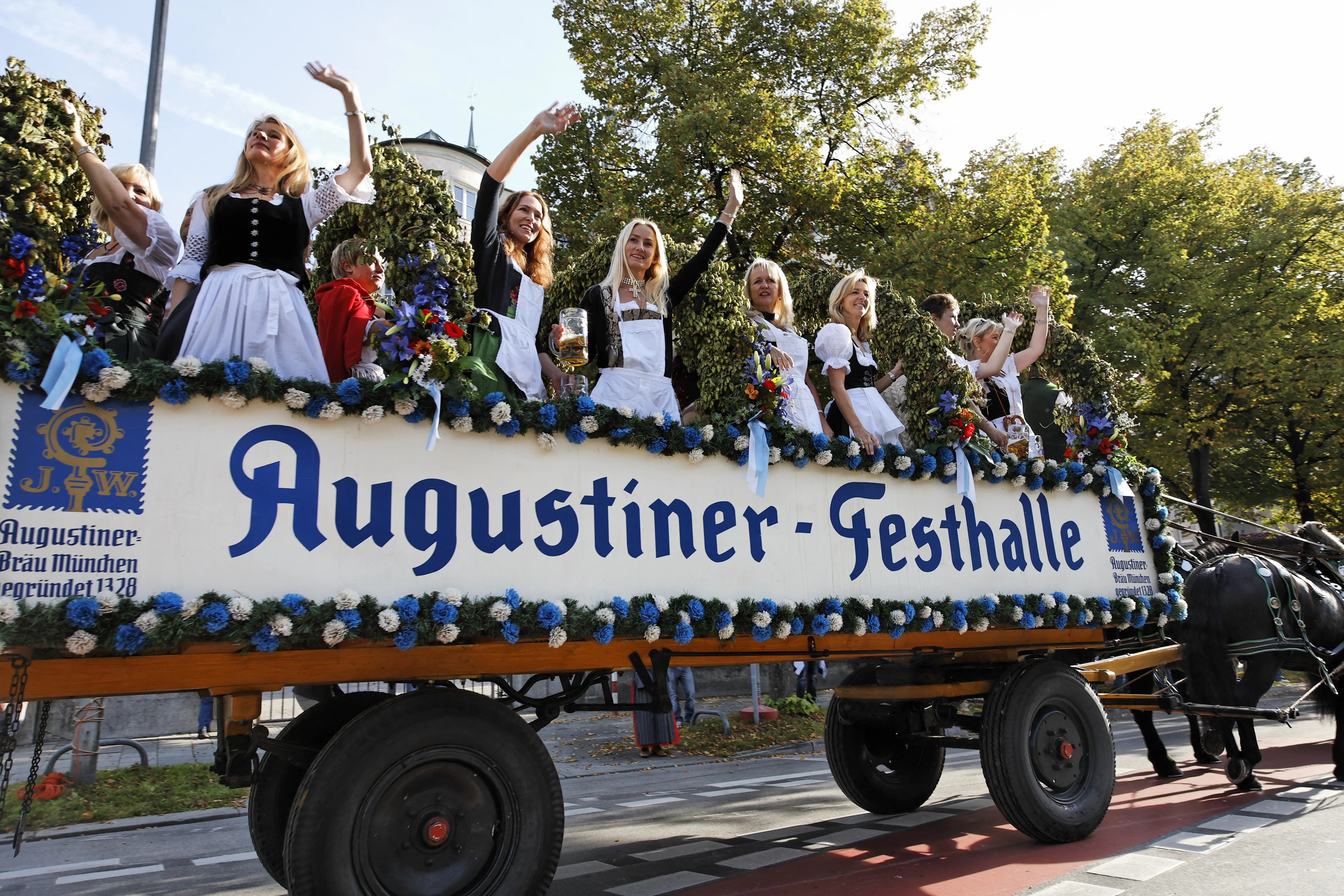 A low-angle, wide-angle shot of a horse-drawn festival wagon during a parade in Munich, Germany.