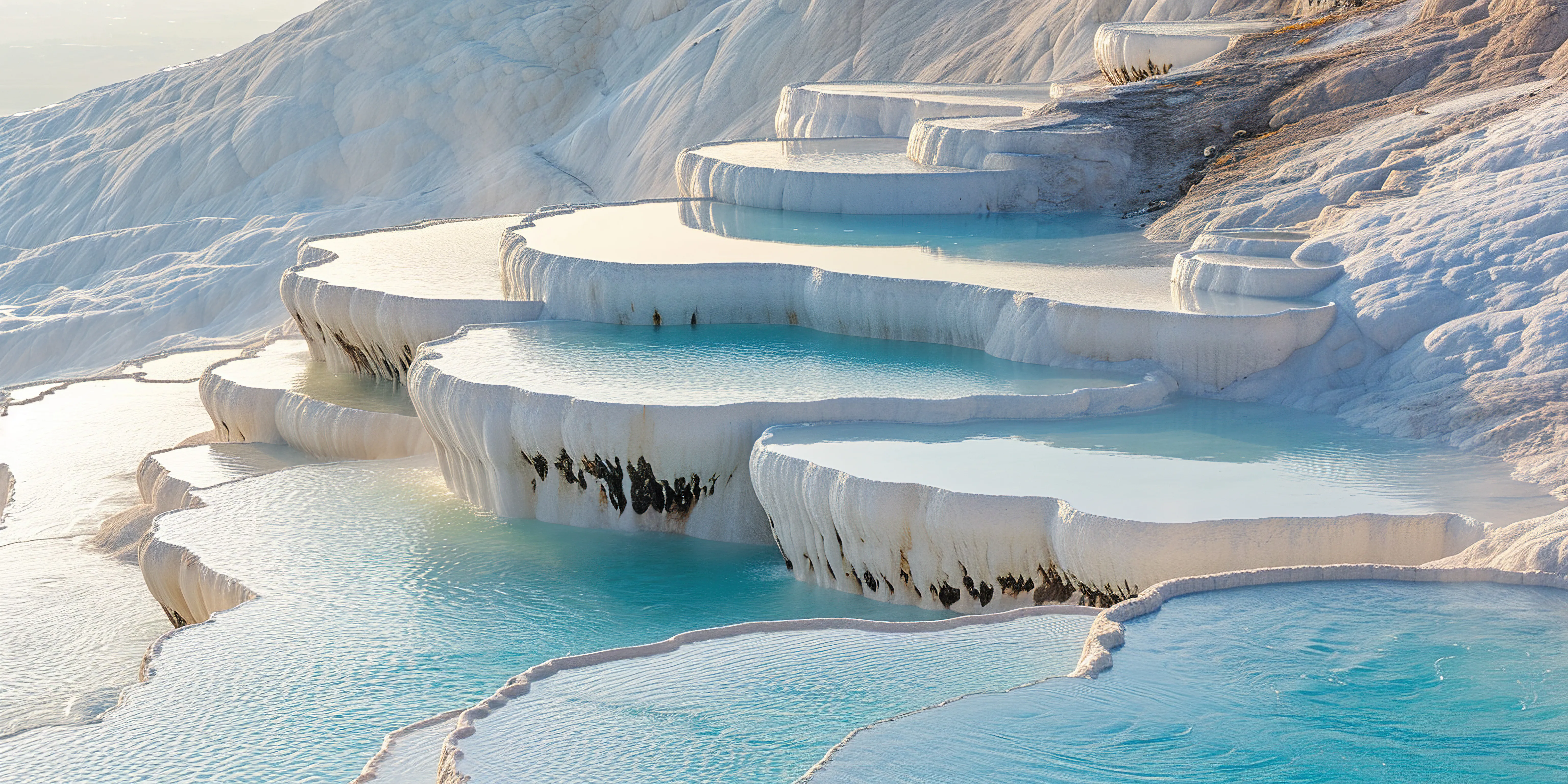 A landscape and nature photograph shows the natural travertine terraces and thermal pools of Pamukkale in Denizli, Turkey
