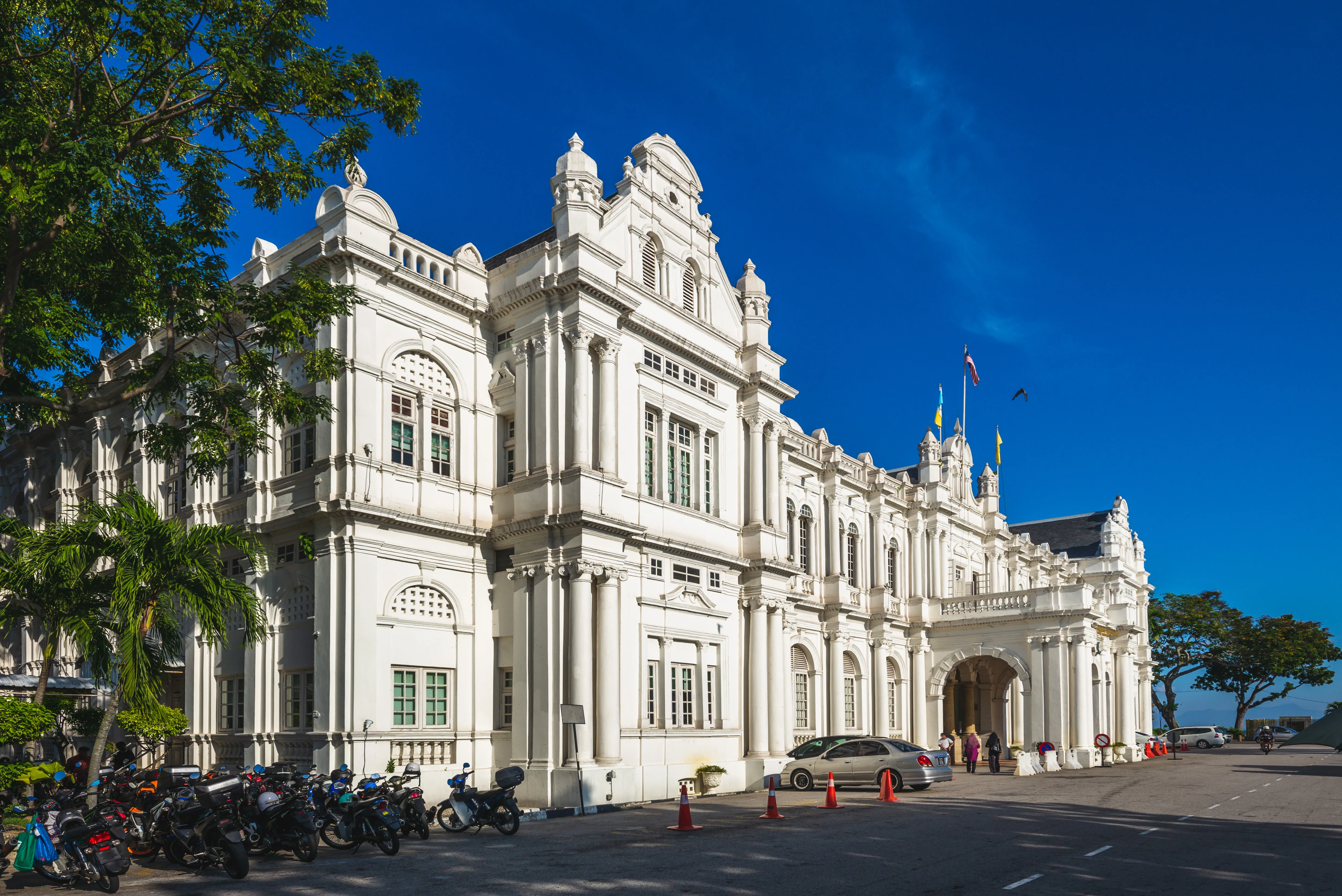 A grand white colonial-style building with intricate architecture under a deep blue sky