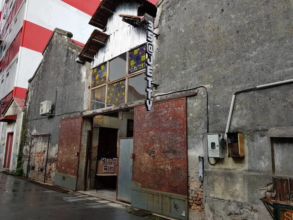 An industrial style building entrance with large, weathered red sliding doors and a sign that reads "35 JETTY