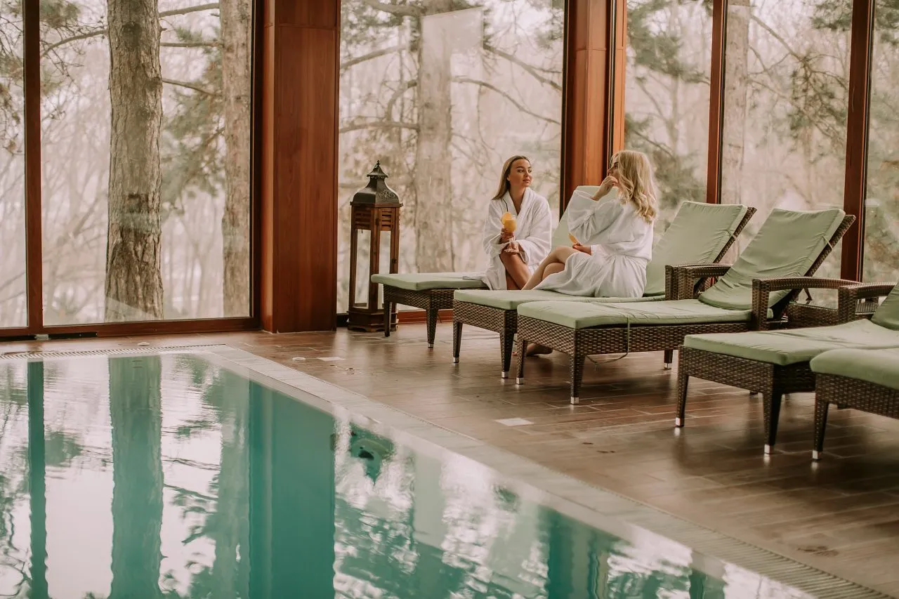 Two women in white robes sitting by the pool at Thermes de Spa, Belgium