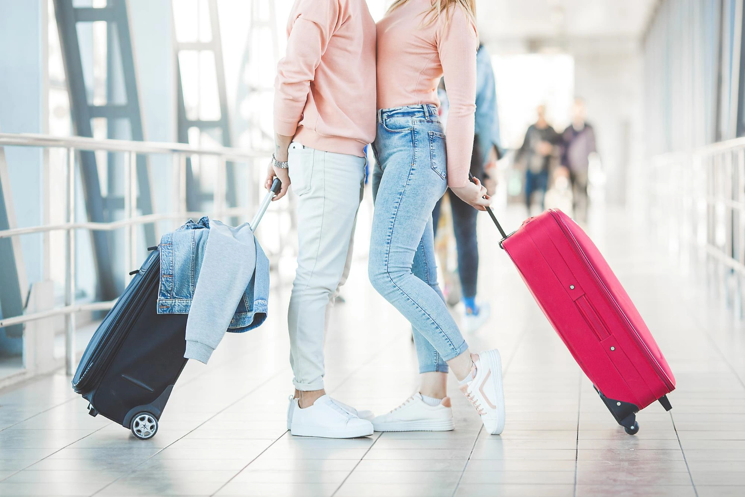 couple-holding-travel-luggages-at-the-airport