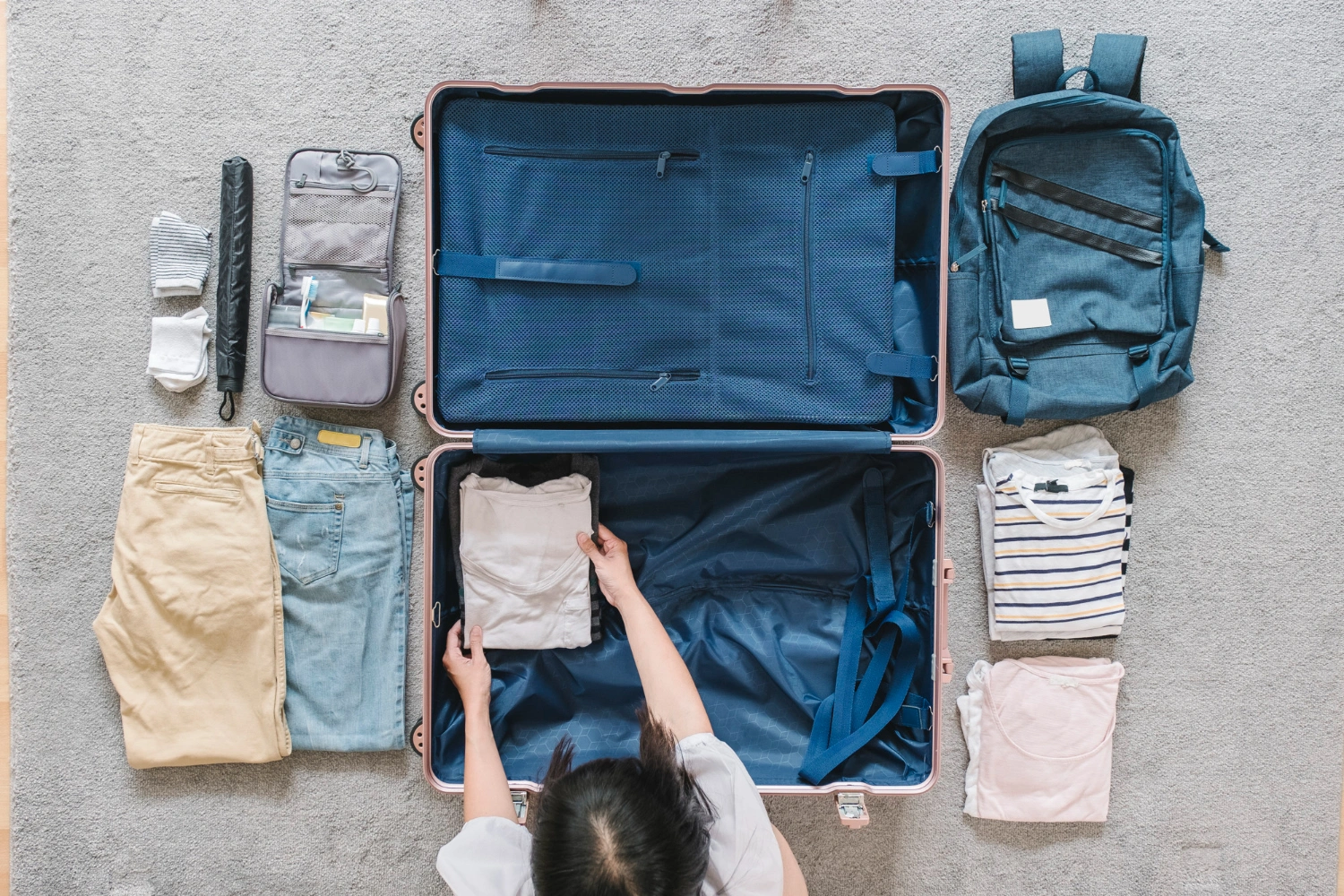 woman-packing-luggage-with-stuff-laying-on-the-ground