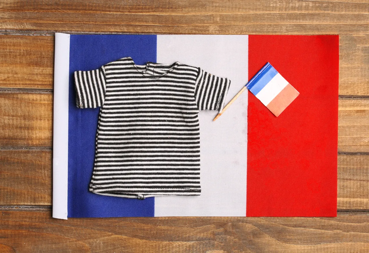 ของฝากจากฝรั่งเศส เสื้อลายทางเบรอตงสีดำสลับขาววางบนธงชาติฝรั่งเศส