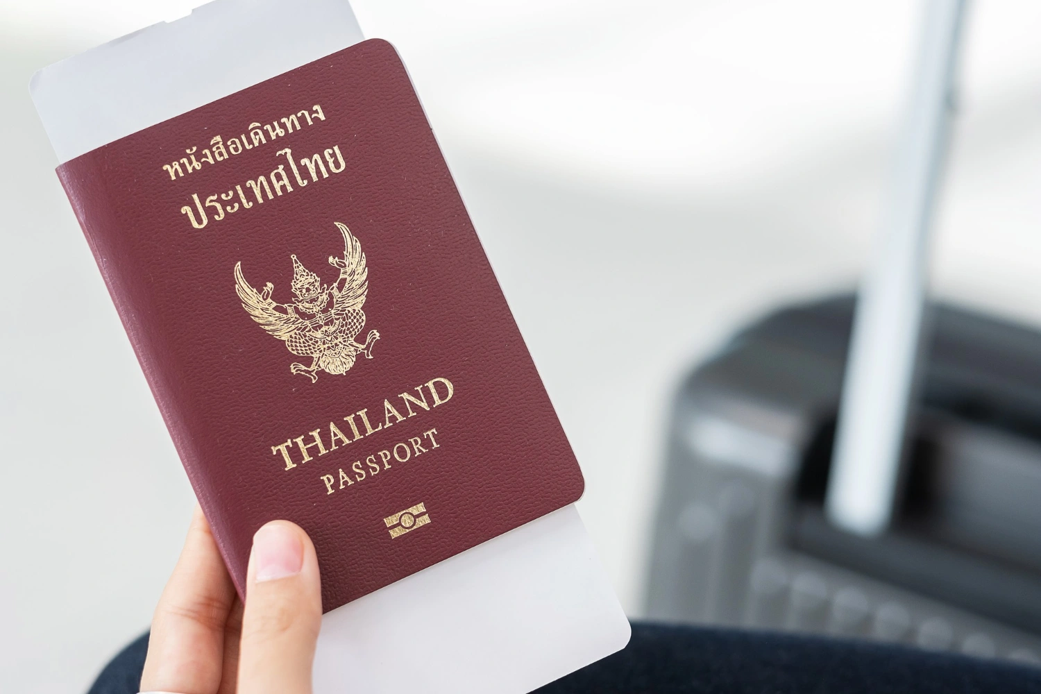 thai-passport-with-boarding-pass-inside-with-travel-luggage-in-the-background